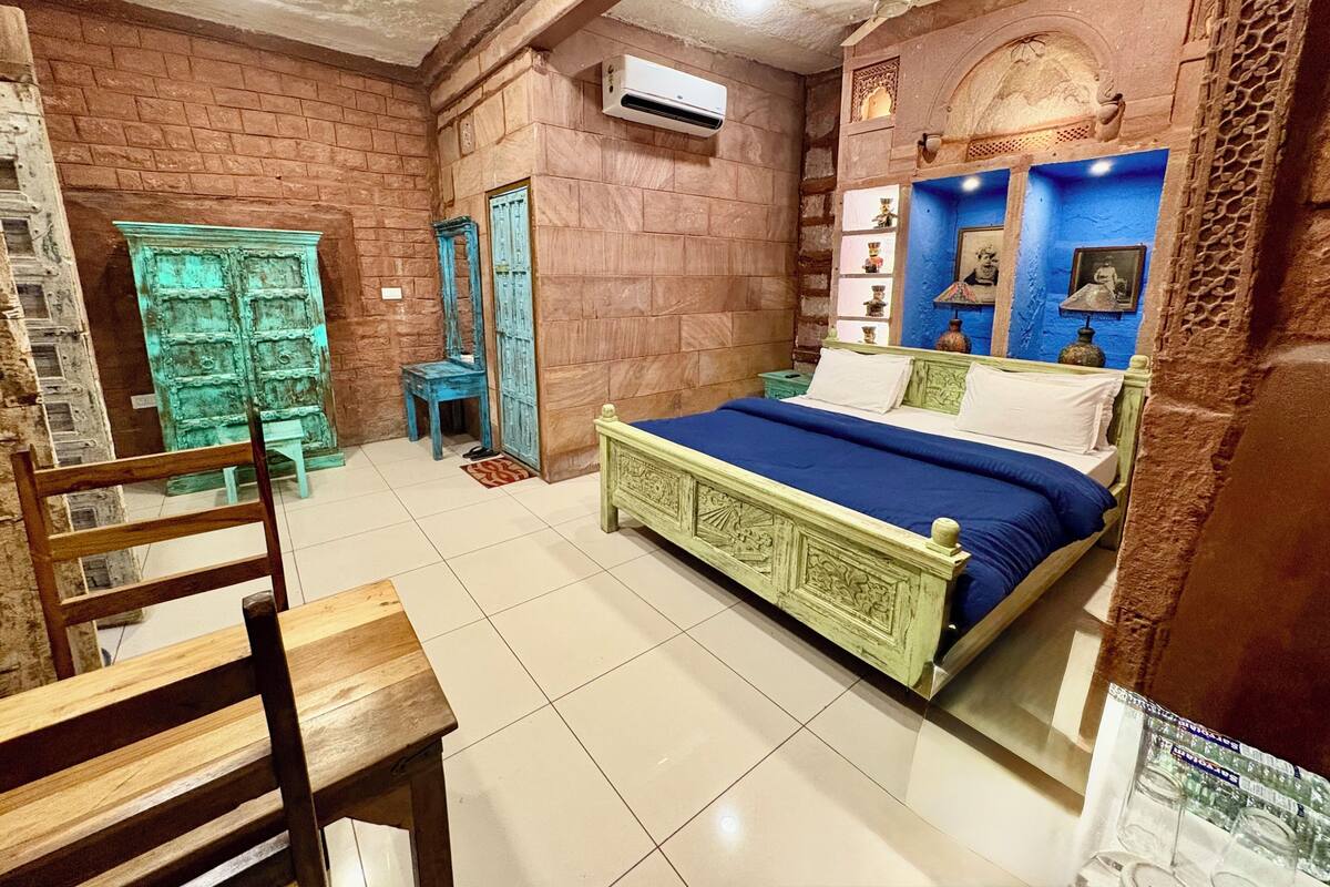 Una habitación con cama, una silla, armario y una mesita.