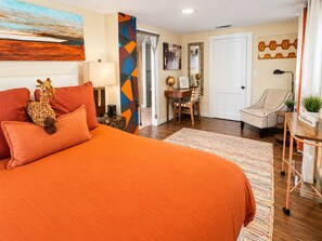 Ein Hotelzimmer mit einem großen Bett, einem Schreibtisch, einem Sessel, einem Globus und einem Bild an der Wand.
