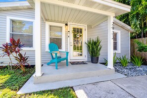 A house with a porch, a blue chair, a potted plant, and a door with a wreath.