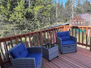 Eine Holzterrasse mit Korbmöbeln und Blick auf Bäume.