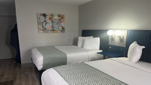 A hotel room with two beds, a nightstand, a wall-mounted lamp, and a painting.