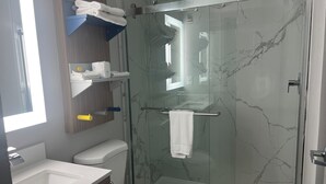 A modern bathroom with a glass-enclosed shower, a white toilet, a sink, and a towel rack.