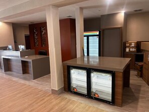 Eine moderne Hotellobby mit einer Rezeption, einem Kühlschrank und einem Getränkeautomaten.