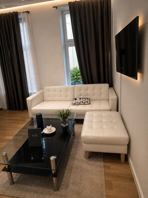 A modern living room with a sectional sofa, a glass coffee table, and a mounted TV. - Oslo city center (Oslo)