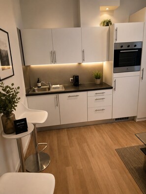 A modern kitchen with white cabinets, a stainless steel sink, a black countertop, and a built-in oven. - Oslo city center (Oslo)
