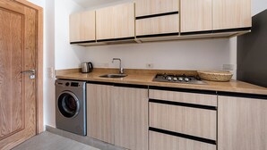 Een praktische keuken met houten kastjes, een wasmachine en een spoelbak.