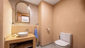 Een badkamer met een wastafel, spiegel, toilet en handdoekhouder.