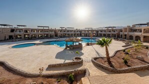 Een resort met meerdere gebouwen, een zwembad en een heldere lucht.