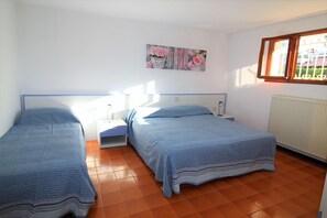 A bedroom with two beds, a nightstand, a window, and a radiator. - Ground-floor Apartment 350m From the Beach (Lignano Sabbiadoro)