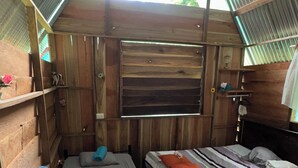 Una habitación rústica de madera con dos camas, una mesa y un ventanal.