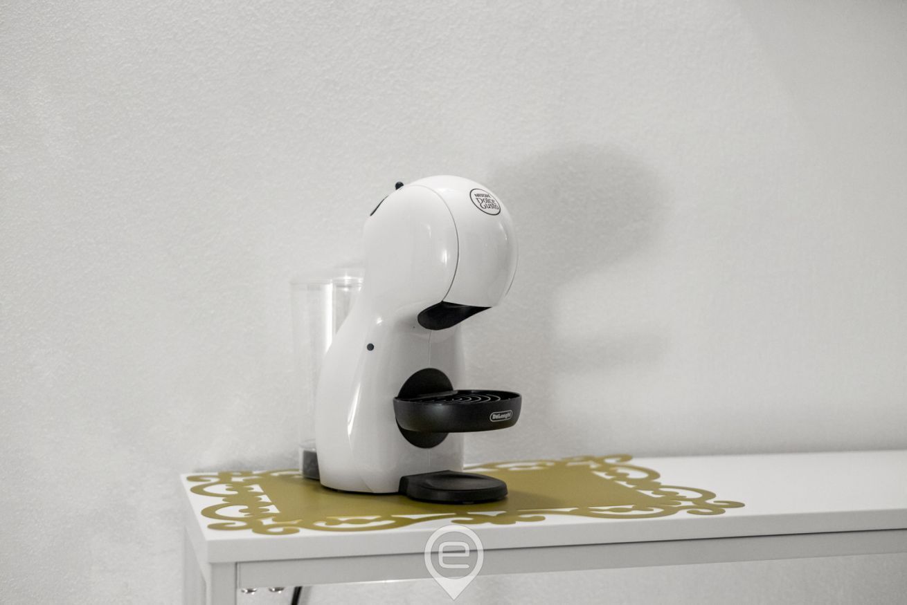 Une machine à café blanche, posée sur une table blanche, ornée d’un motif décoratif doré.