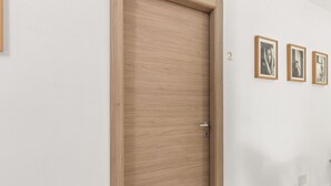 Ein Flur mit einer Holztür, einer Wand mit drei gerahmten Bildern und der Zahl 2 an der Wand.