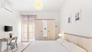Ein Schlafzimmer mit einem Bett, einem Schreibtisch mit Stuhl, einem Fernseher und einem Spiegel.