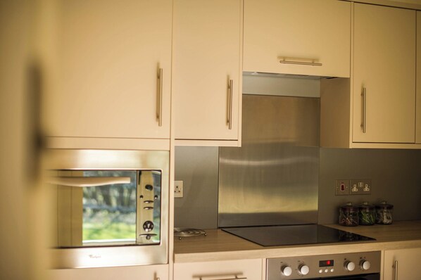 Cozinha com eletrodomésticos de aço inoxidável, forno embutido e micro-ondas.