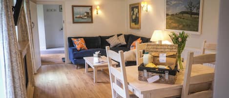 A cozy living room with a wooden floor, a sofa, a table with a basket, and a painting on the wall.