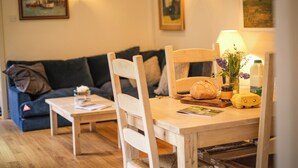 Ein gemütliches Wohnzimmer mit einem Holzesstisch, einer Couch und Wandlampen.