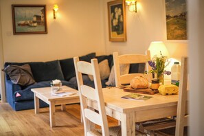 Uma sala de estar aconchegante com uma mesa de jantar de madeira, um sofá e luminárias fixadas na parede.