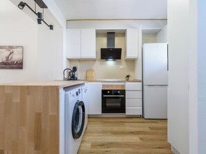Een kleine keuken met een wasmachine, oven en een inbouwmagnetron.