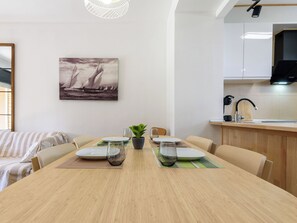 A dining area with a wooden table, chairs, a potted plant, and a painting of sailboats. - Tramuntana II by Interhome (Salou)