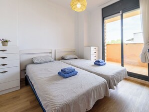 Un dormitorio con dos camas, un aparador, un mueble pequeño y un balcón con vistas.