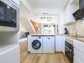 A compact kitchen with a washing machine, a microwave, and a wooden countertop. - Tramuntana II by Interhome (Salou)