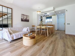 A modern living room with a sofa, dining table, and a round wooden coffee table. - Tramuntana II by Interhome (Salou)