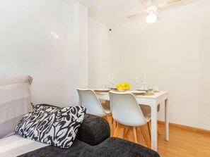 Une pièce moderne comprenant un canapé, un coussin à motifs, une table à manger avec des chaises et un ventilateur de plafond.