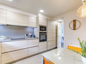A modern kitchen with wooden cabinets, a built-in oven, and a white countertop. - La Suntuosidad – Torremirona by Interhome (Navata)