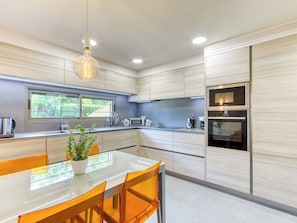 A modern kitchen with a built-in oven, microwave, and a window overlooking greenery. - La Suntuosidad – Torremirona by Interhome (Navata)