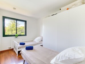 A bedroom with two beds, a window with a view of trees, a radiator, and a white wardrobe. - La Suntuosidad – Torremirona by Interhome (Navata)
