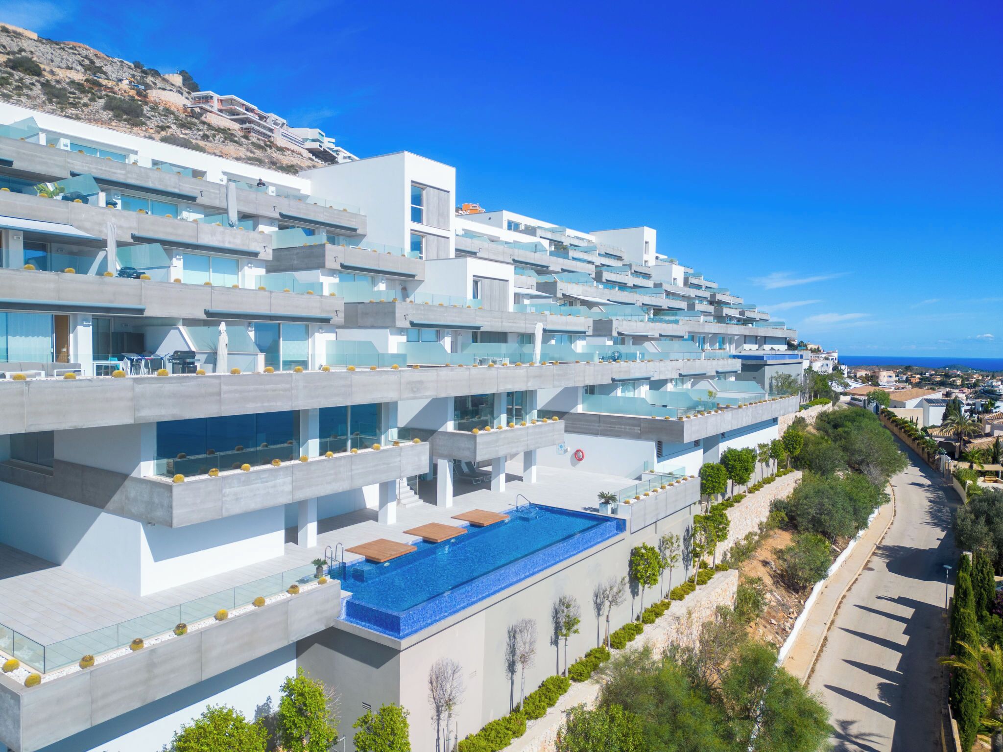 Un hôtel moderne doté d’une piscine sur le toit, de nombreux balcons et offrant une vue sur la côte.