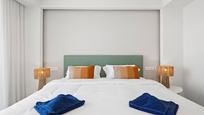 A hotel room with a large bed, two bedside lamps, a green headboard, and two blue towels. - Blue Infinity I by Interhome (Moraira)