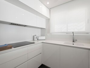 A modern kitchen with white cabinetry, a built-in stove, and a window above the sink. - Blue Infinity I by Interhome (Moraira)