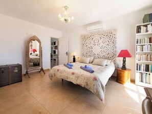 A bedroom with a bed, a dresser, a mirror, a bookshelf, and an air conditioning unit. - Vacation home Lotus by Interhome (Almuñécar)