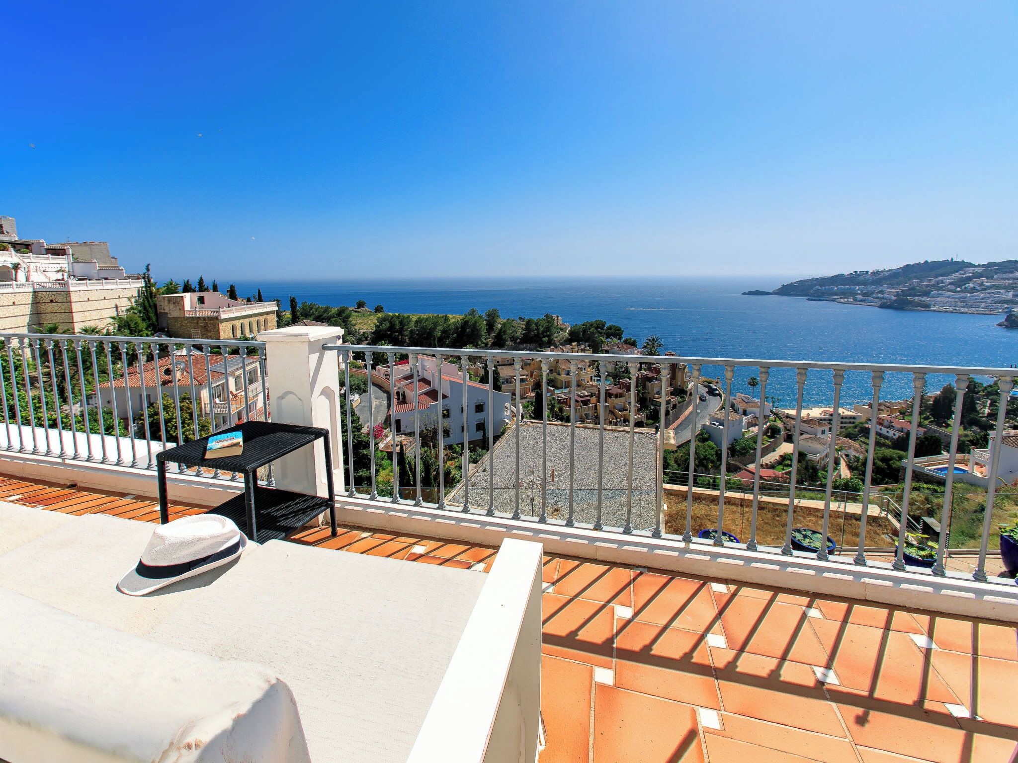 Un balcon avec vue sur la mer, un chapeau et une petite table.