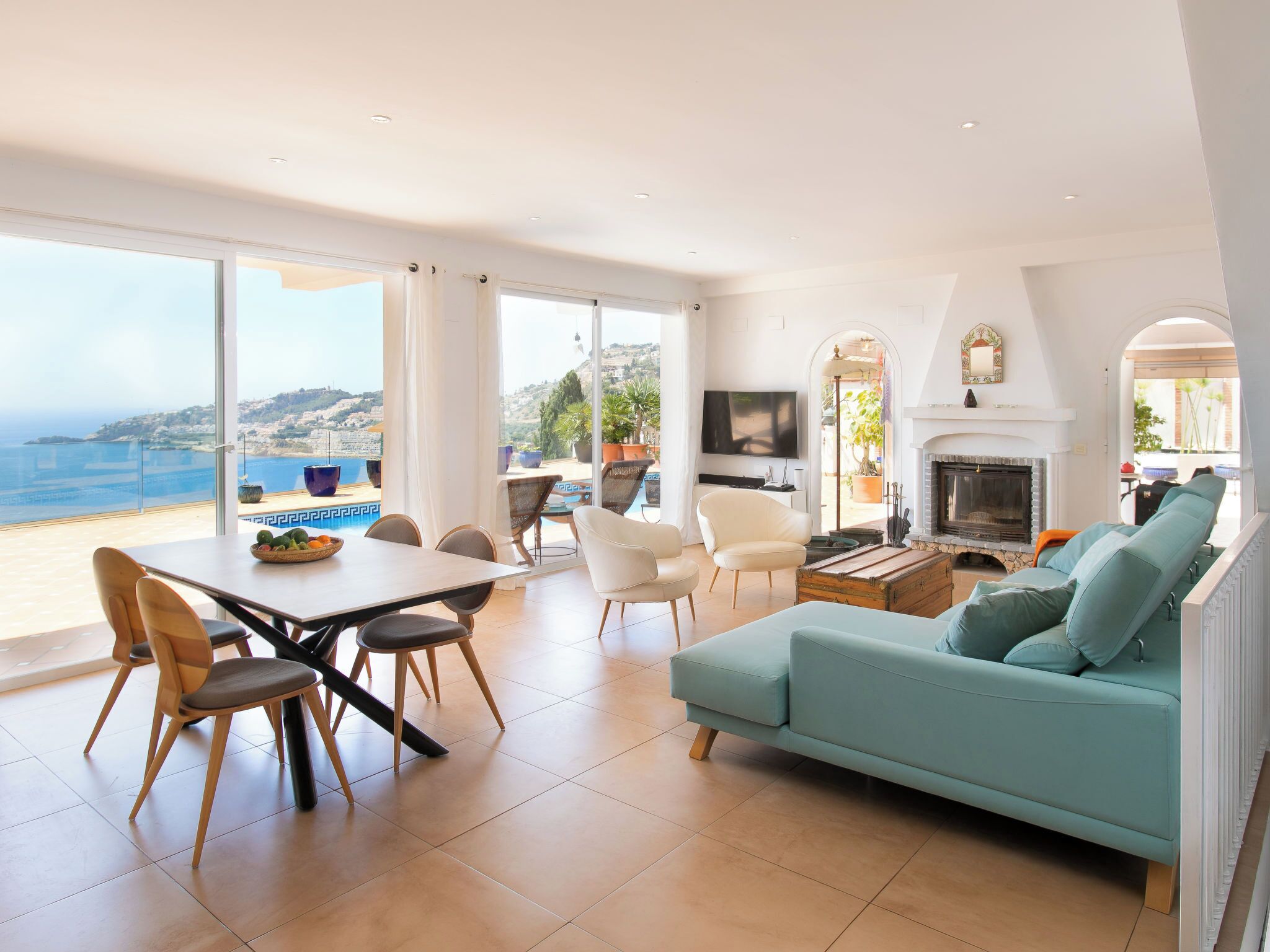A spacious living area with a sofa, dining table, chairs, and a fireplace.