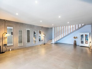 Un intérieur spacieux avec un mur en béton, un escalier et une bibliothèque.