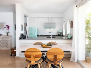A modern kitchen with a central island, two wooden chairs, a fruit bowl, and a teal refrigerator. - Vacation home Lotus by Interhome (Almuñécar)