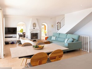 A modern living room with a fireplace, a sofa, a TV, and a dining area. - Vacation home Lotus by Interhome (Almuñécar)
