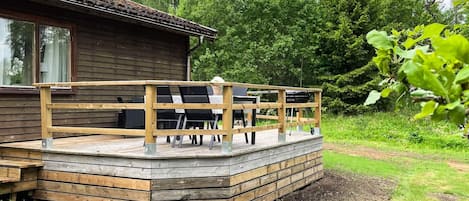 A wooden deck with outdoor furniture, a dining table, and chairs.