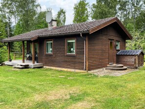 A wooden cabin with a porch, a small attached shed, and a chimney. - 4 Person Holiday Home in Hacksvik (Håcksvik)