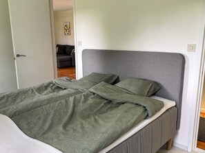 A single bed with a grey headboard and green patterned bedding in a room with white walls. - 4 Person Holiday Home in Hacksvik (Håcksvik)