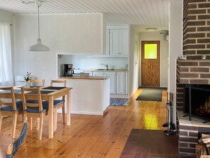 A modern kitchen with white cabinets, a central island, and a dining area with wooden chairs. - 4 Person Holiday Home in Hacksvik (Håcksvik)