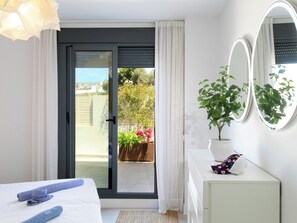 A bedroom with a bed, a potted plant, a mirror, and a view of the outdoors. - Sea Garden by Interhome (Torrox Costa)