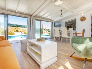 A modern living room with a pool view, a dining area, and a kitchen. - Vacation home Tuli by Interhome (Lloret de Mar)