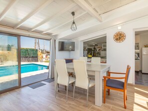 A modern interior with a dining area, kitchen, and a view of an outdoor swimming pool. - Vacation home Tuli by Interhome (Lloret de Mar)