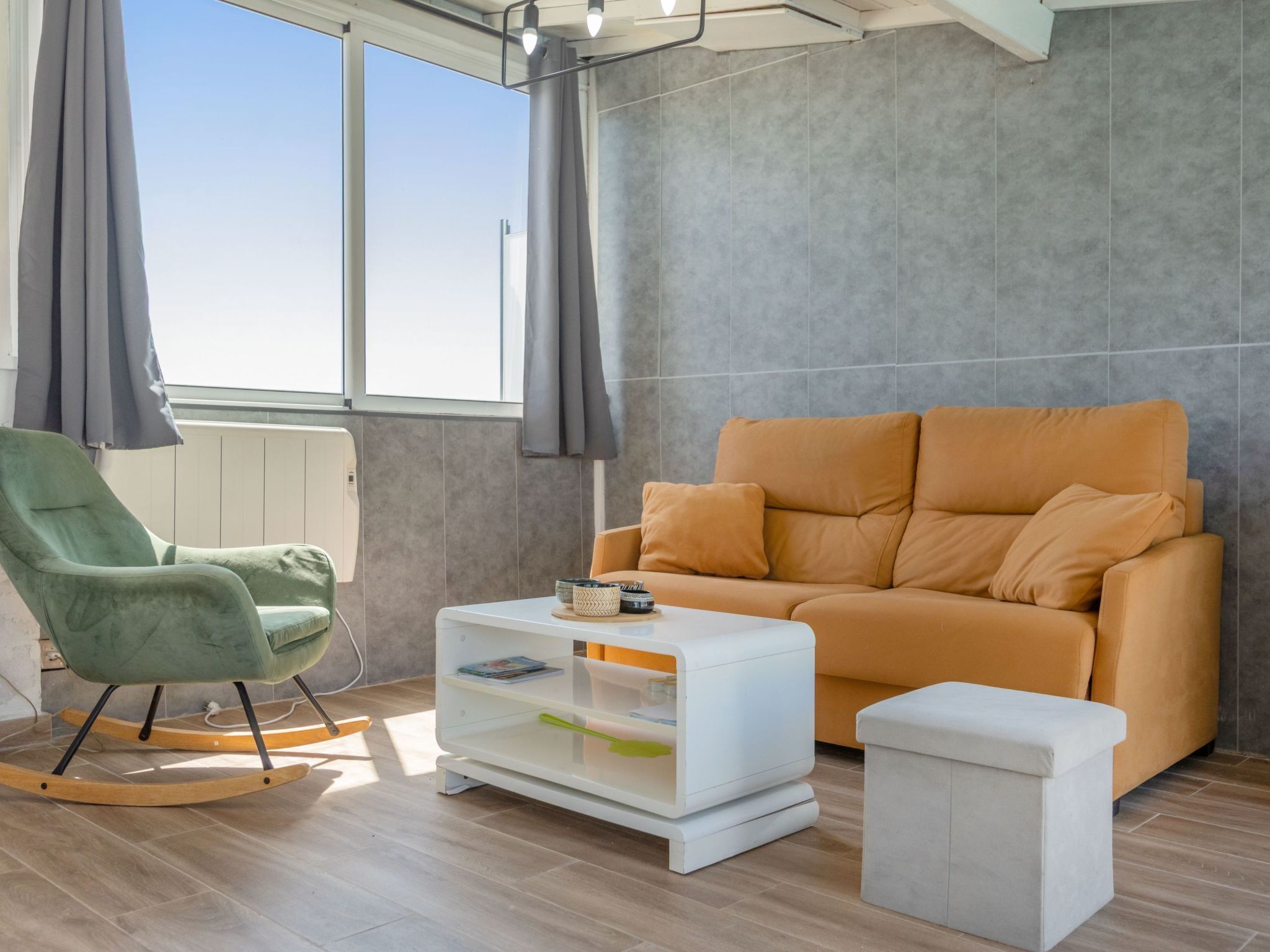 A modern living room with a green rocking chair, a white coffee table, and an orange sofa.