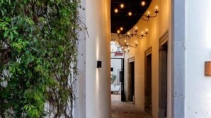 Un couloir doté d’un sol carrelé, d’une porte en arc de cercle et d’un mur recouvert de plantes grimpantes.