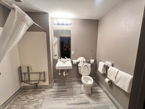 Et badeværelse med brusebad, toilet, håndvask og et spejl.