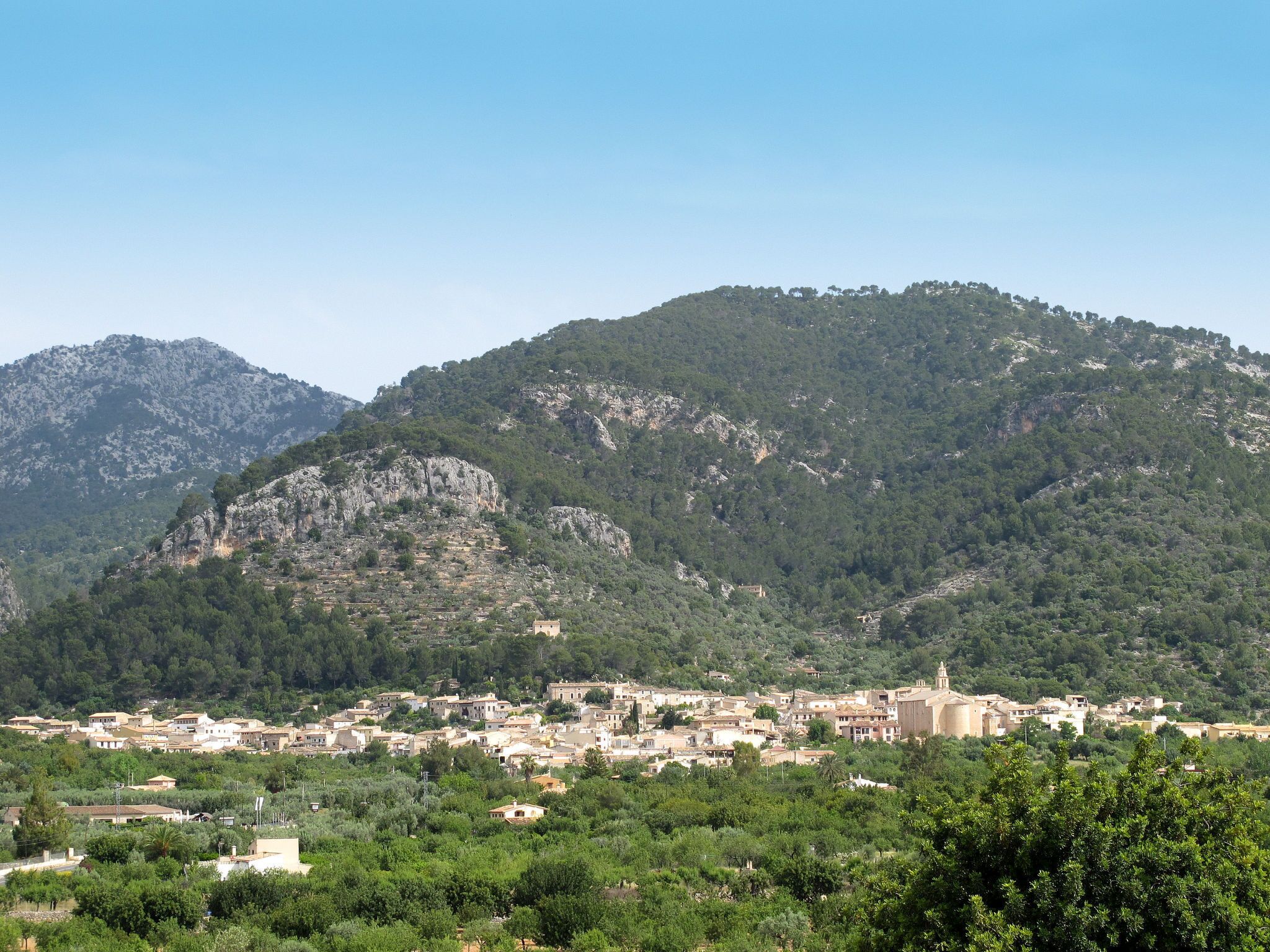 A town nestled in a valley with a backdrop of mountains, featuring a mix of traditional and modern architecture.